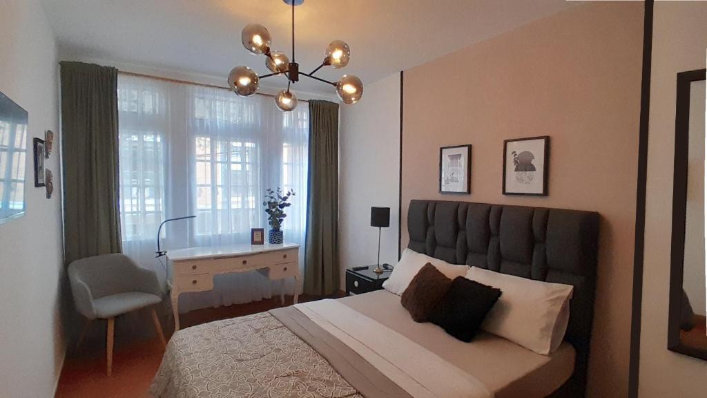 Un dormitorio con una cama, un escritorio y una lámpara de araña. en Habitacion Independiente Baño privado en La Macarena, en Bogotá