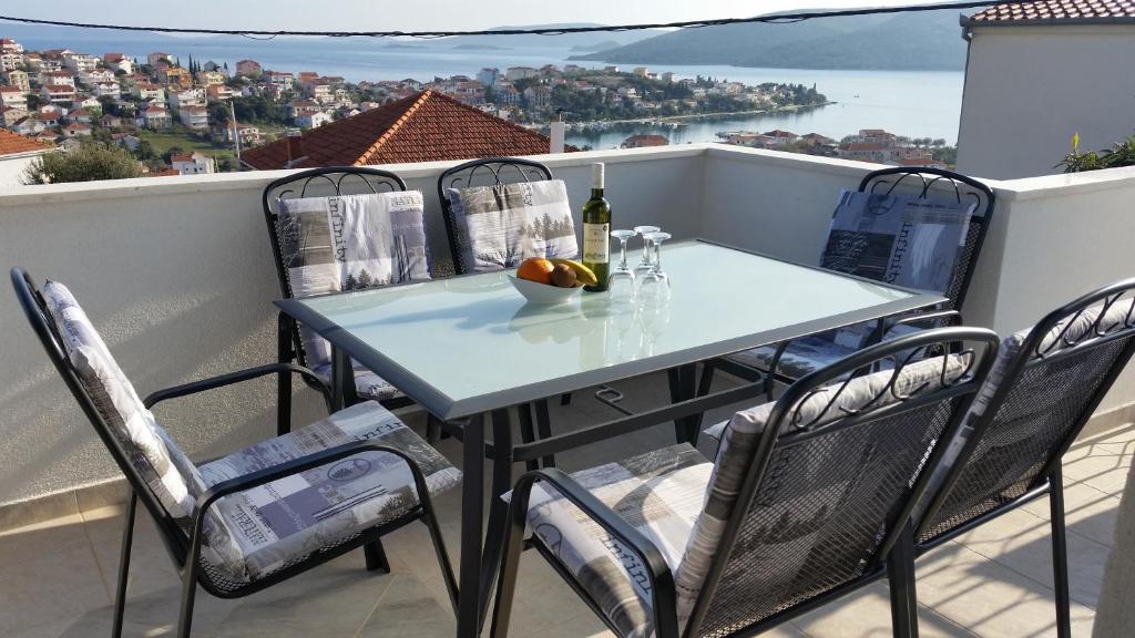 a table and chairs on a balcony with a bottle of wine at Apartments Plejic in Seget Vranjica