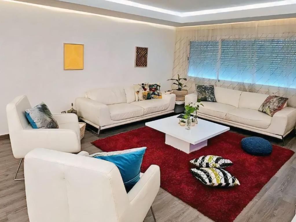 a living room with white couches and a red rug at Maison Ali in Ville Nouvelle