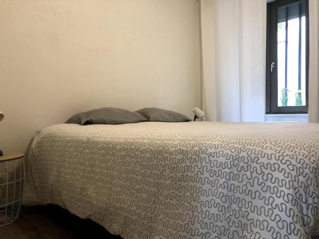 a bedroom with a bed with a blanket and a window at Arènes 1 à deux pas du centre historique in Besançon