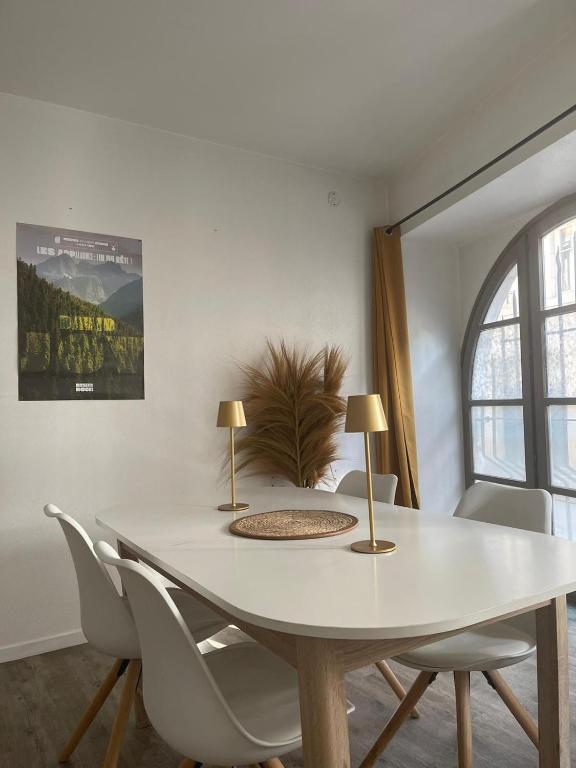 - une table à manger blanche avec des chaises blanches et 2 lampes dans l'établissement Arènes 1 à deux pas du centre historique, à Besançon