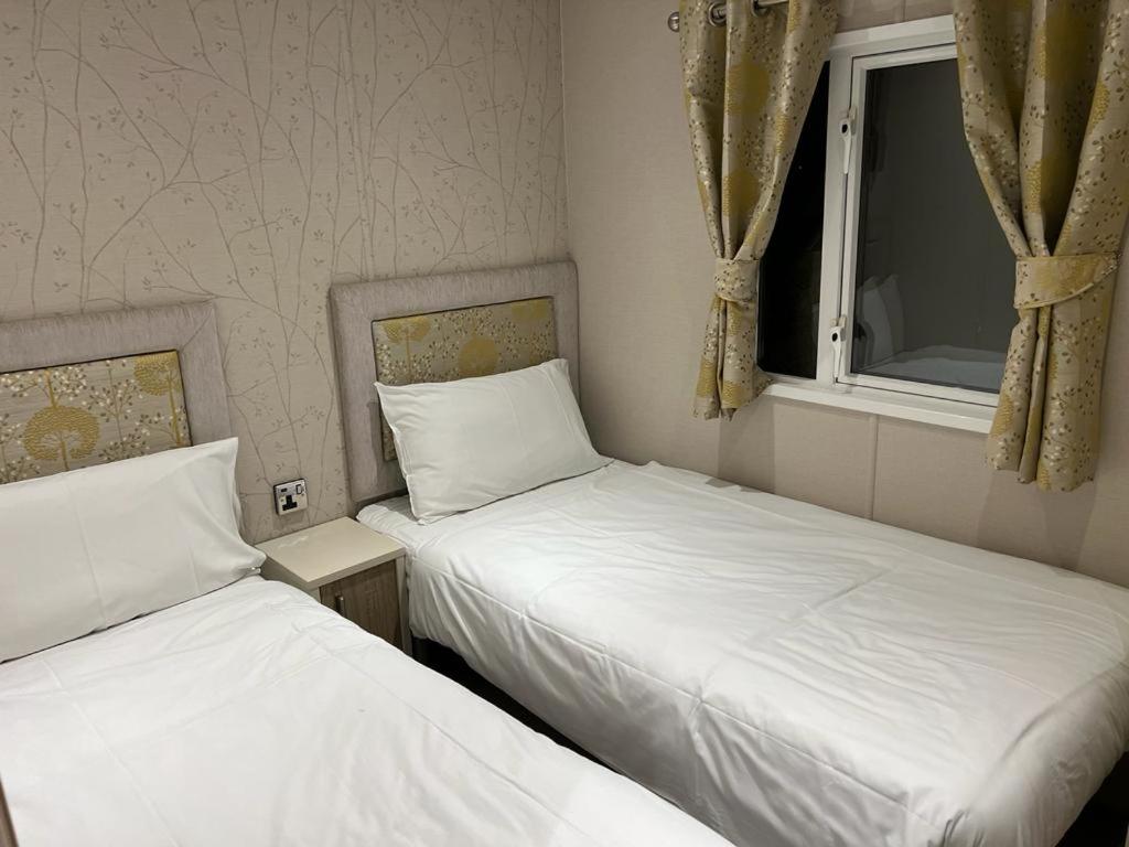 two beds in a small room with a window at The Lakeside 55 Caravan 8 Bert with Hot Tub at Tattershall Lakes in Tattershall