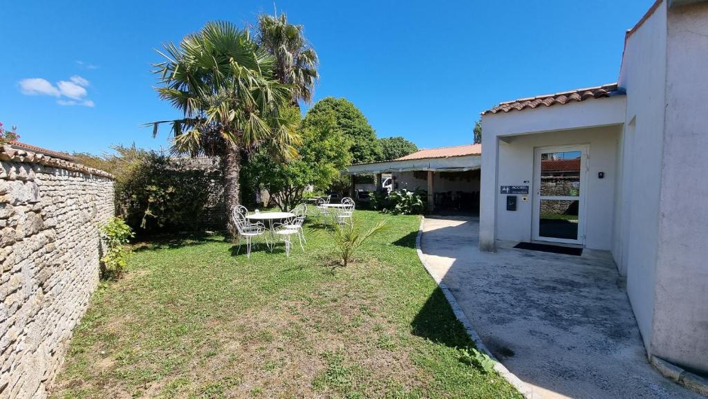 a yard with a table and chairs and a building at La Marie Galante Appart'Hotel in Saint-Georges-dʼOléron