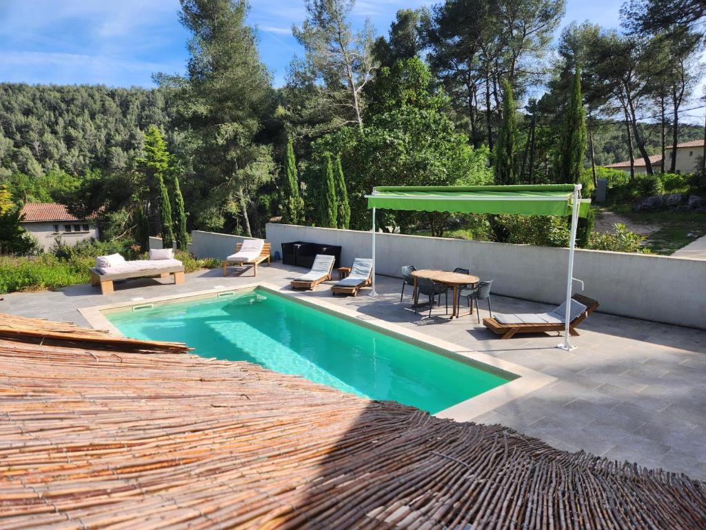 - une piscine avec une table et un auvent vert dans l'établissement La Villa des Rouvières, à LʼÉtoile
