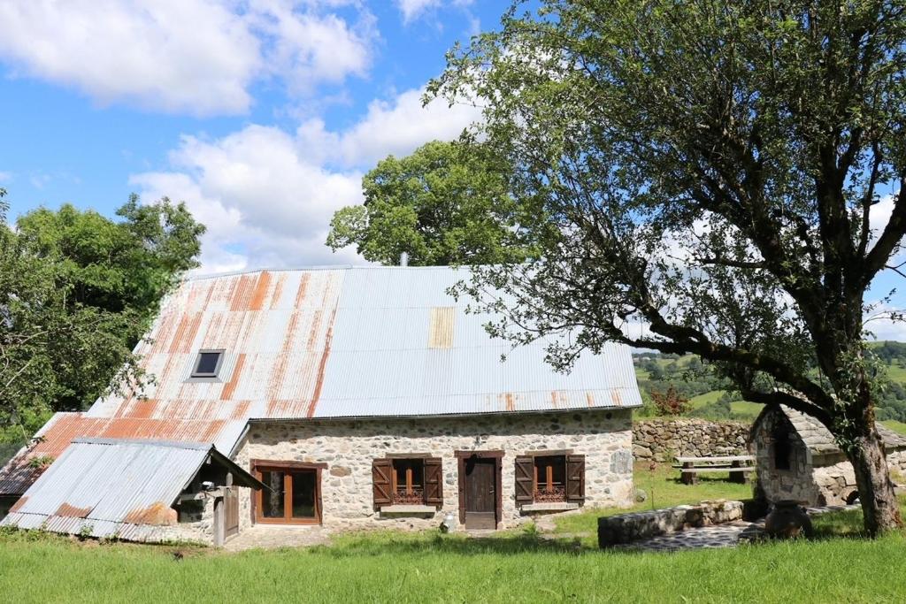 an old stone barn with an orange roof at La Fermette de Loucheyre in Saint-Amandin