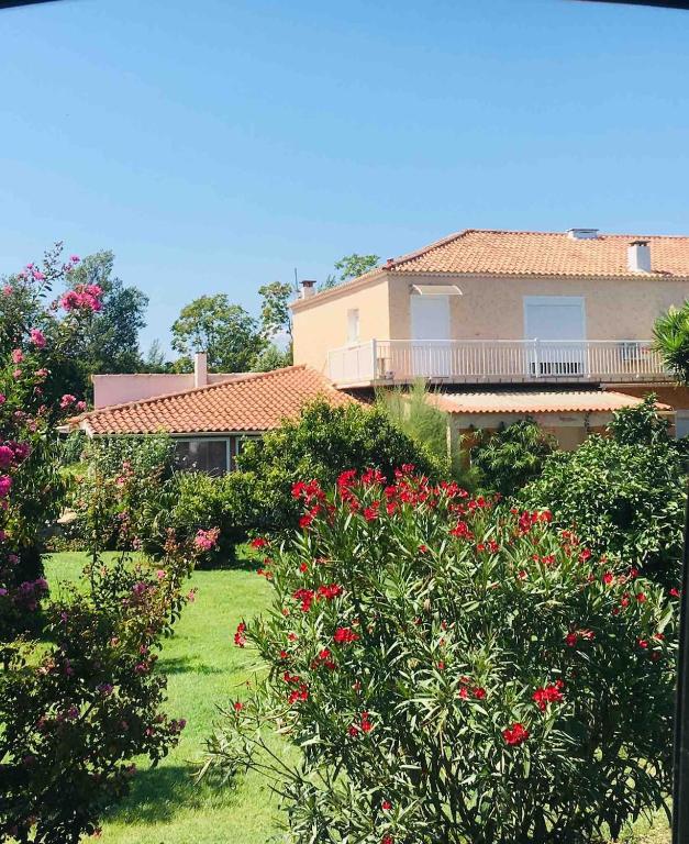 a house with a yard with red flowers at Appartement confort in Île de Diane