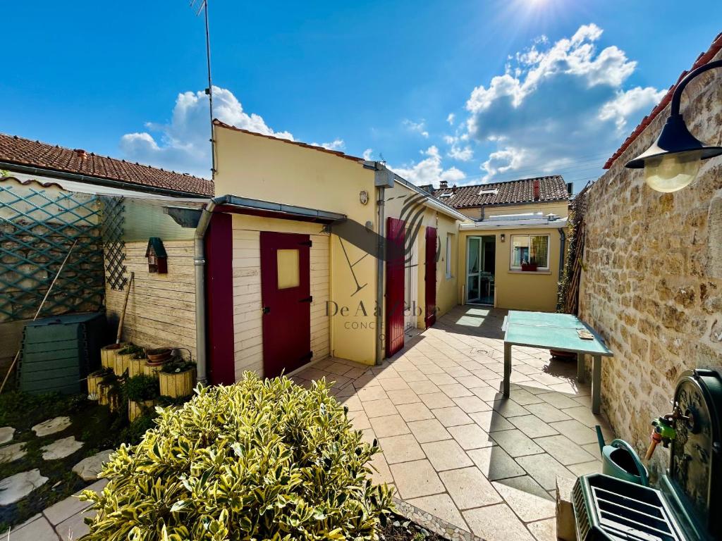 eine Terrasse mit einem Tisch in der Mitte von zwei Gebäuden in der Unterkunft Le Ferney - Proche du centre-ville et des thermes in Rochefort