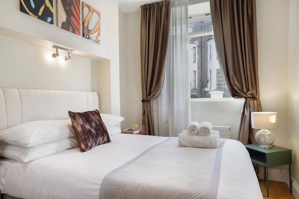 Hotel HR2 - Charming 1-Bed near Holland Park - by Short Stories London, a bedroom with a white bed and a window at HR2 - Charming 1-Bed near Holland Park - by Short Stories London in London