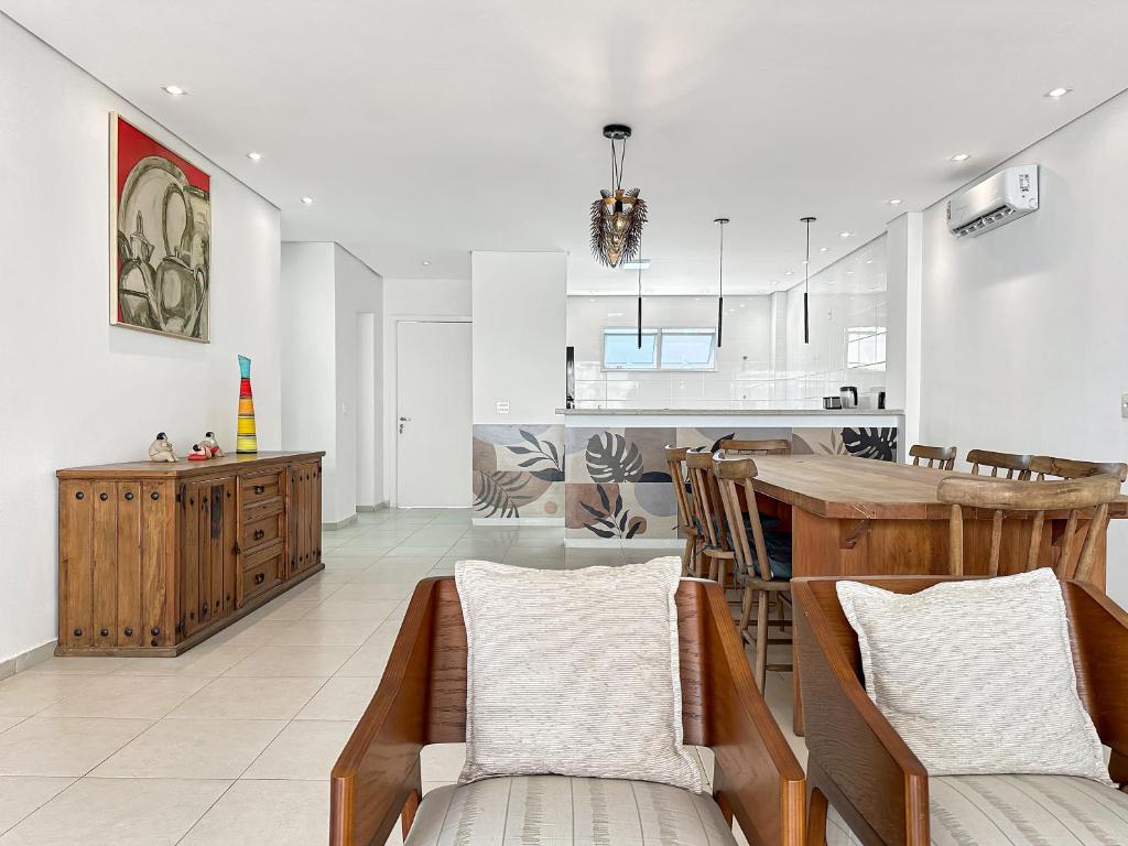 a kitchen and living room with a table and chairs at 100 metros da praia - Condomínio - 3 suítes - Churrasqueira in Guarujá