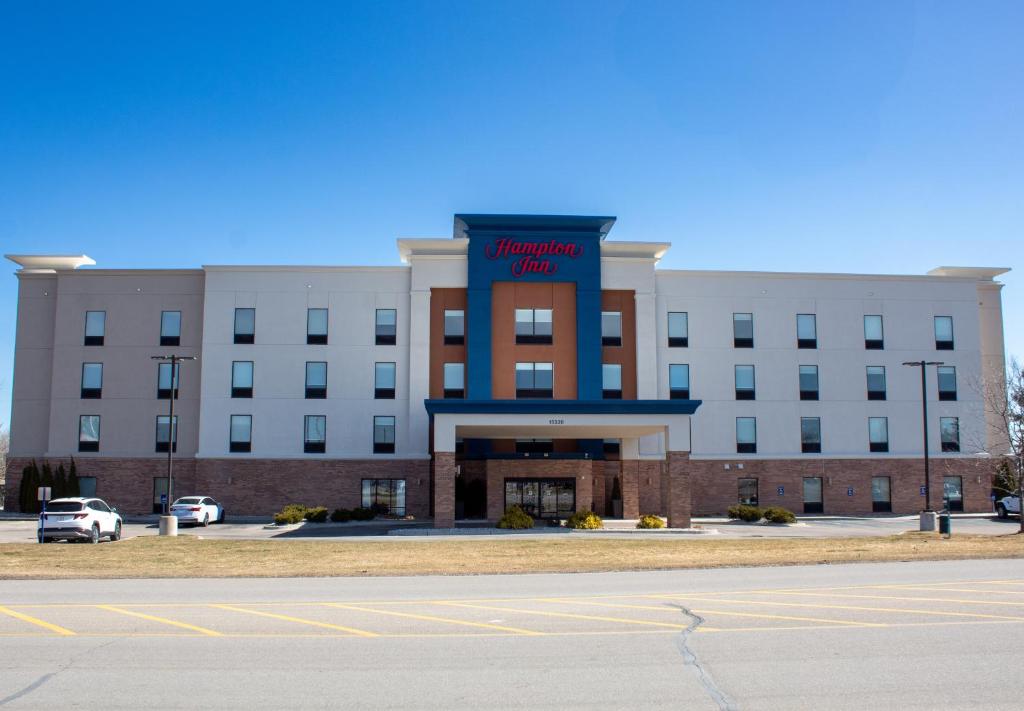 大瀑布城Hampton Inn & Suites Big Rapids, Mi的一座白色的大建筑,上面有蓝色的标志