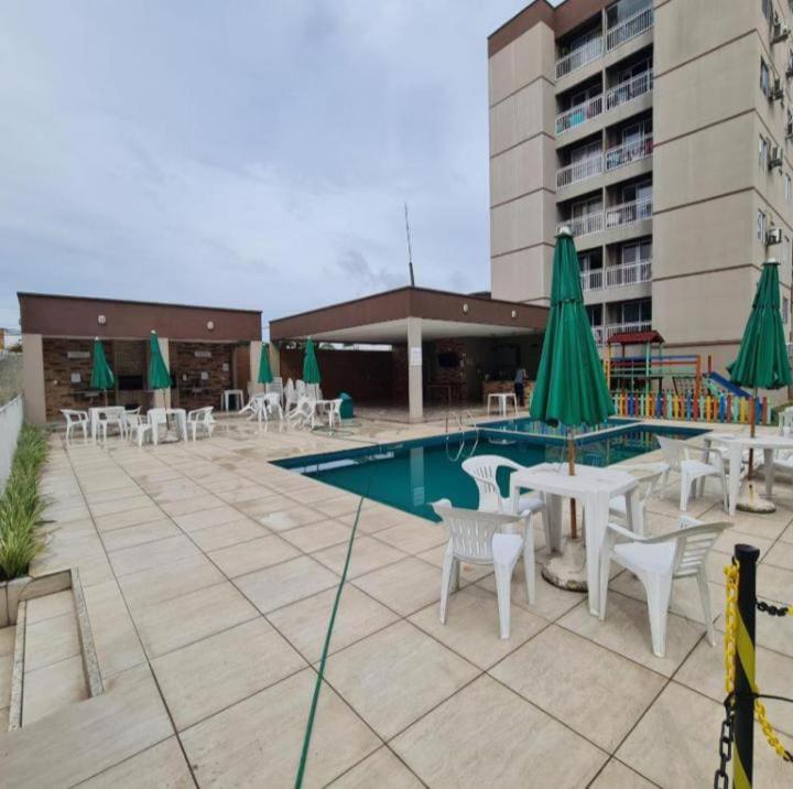 a pool with tables and chairs and green umbrellas at Ap close cop30 confort in Ananindeua