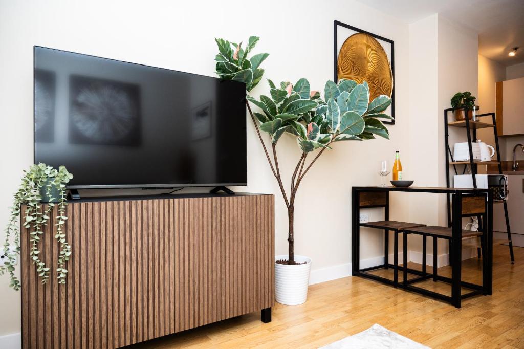a living room with a flat screen tv on a wooden stand at Modern City 2 bed Apartment with FREE Parking & WIFI & NETFLIX in Hunslet