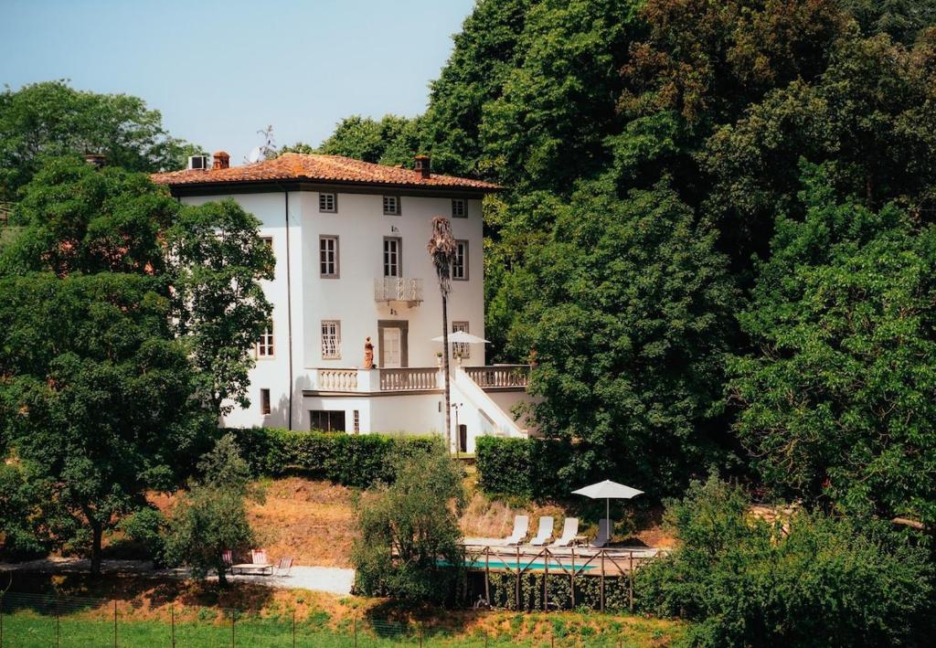 a large white house in the middle of trees at Villa Bianca charming Tuscany house with pool in Lucca