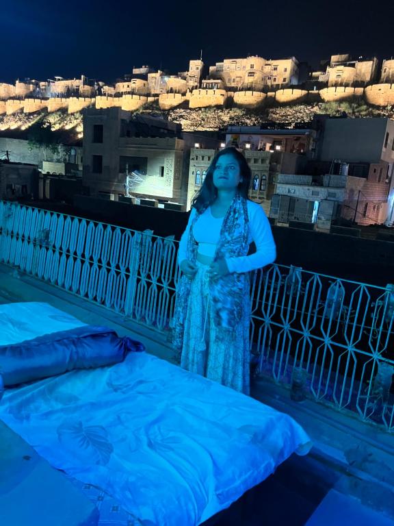 una donna che di notte si alza in piedi su un balcone di Mirvana Guest House & Camel safari a Jaisalmer