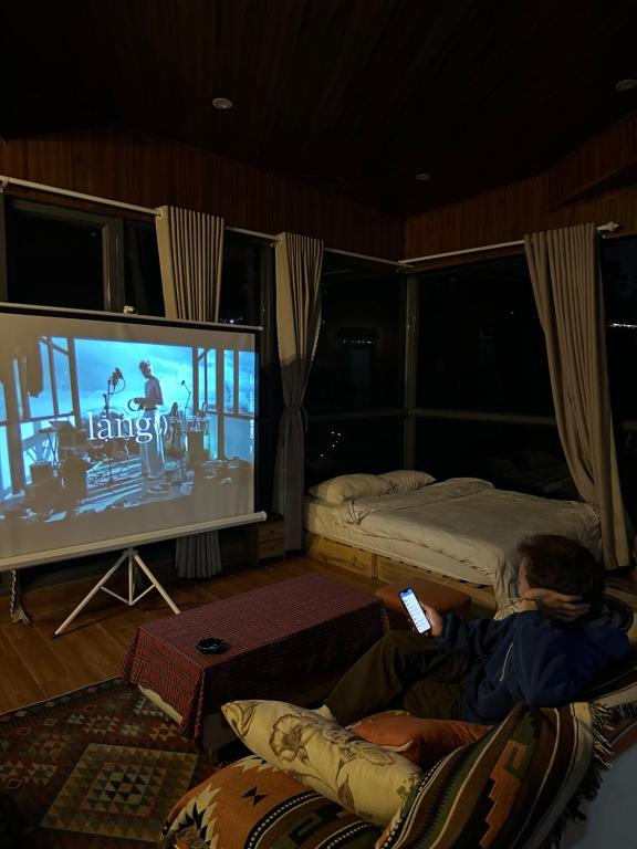 Xuan AnにあるChu Houseの椅子に座ってテレビで映画を見ている男