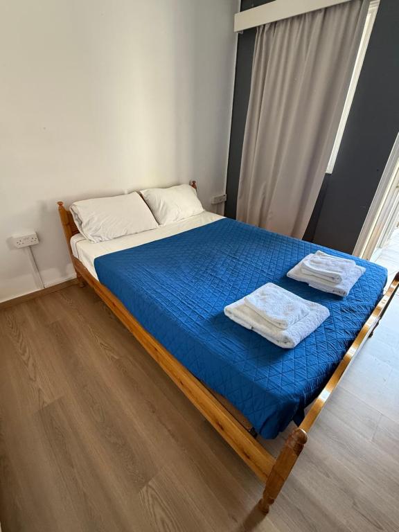 Una cama con sábanas azules y toallas blancas. en D Pitsillos Homes luxury, en Lárnaca