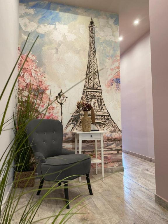 a chair in a room with a mural of the eiffel tower at Paris - Szeged City Center in Szeged