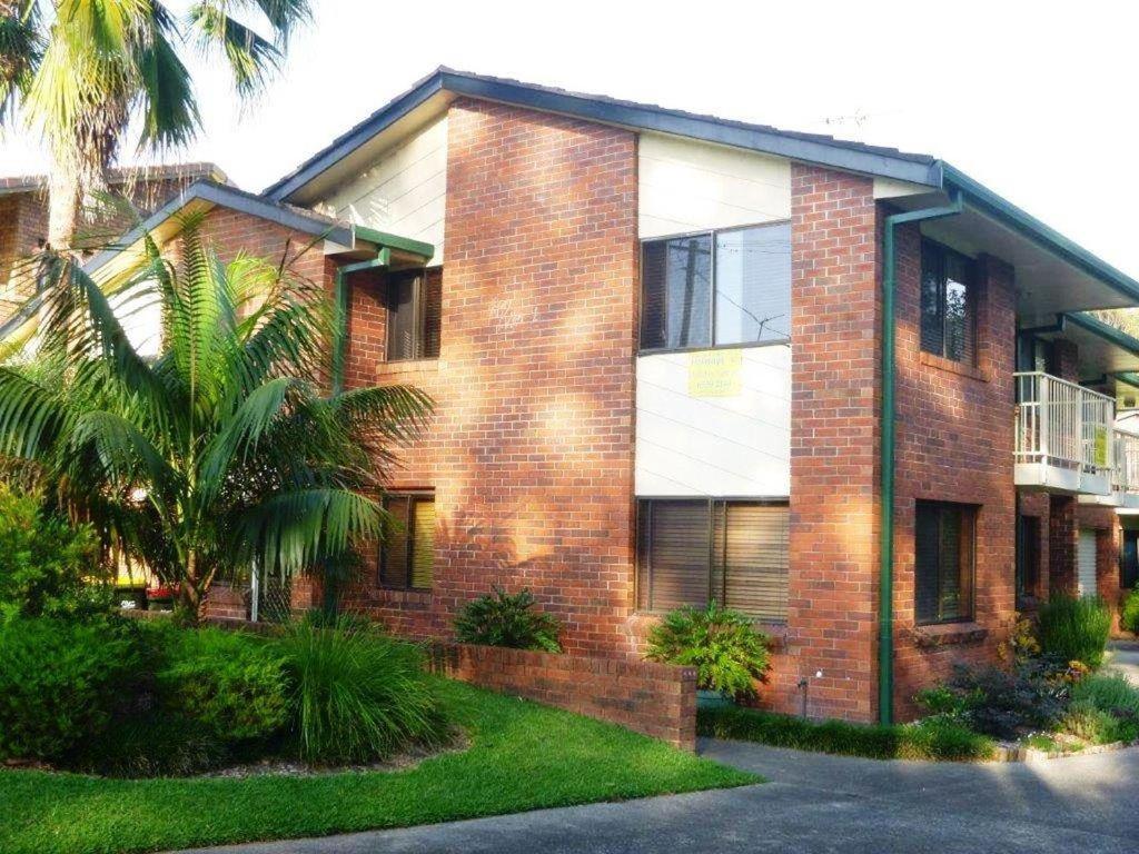 a brick house with a palm tree in front of it at Parkview 1- Black Head NSW in Hallidays Point