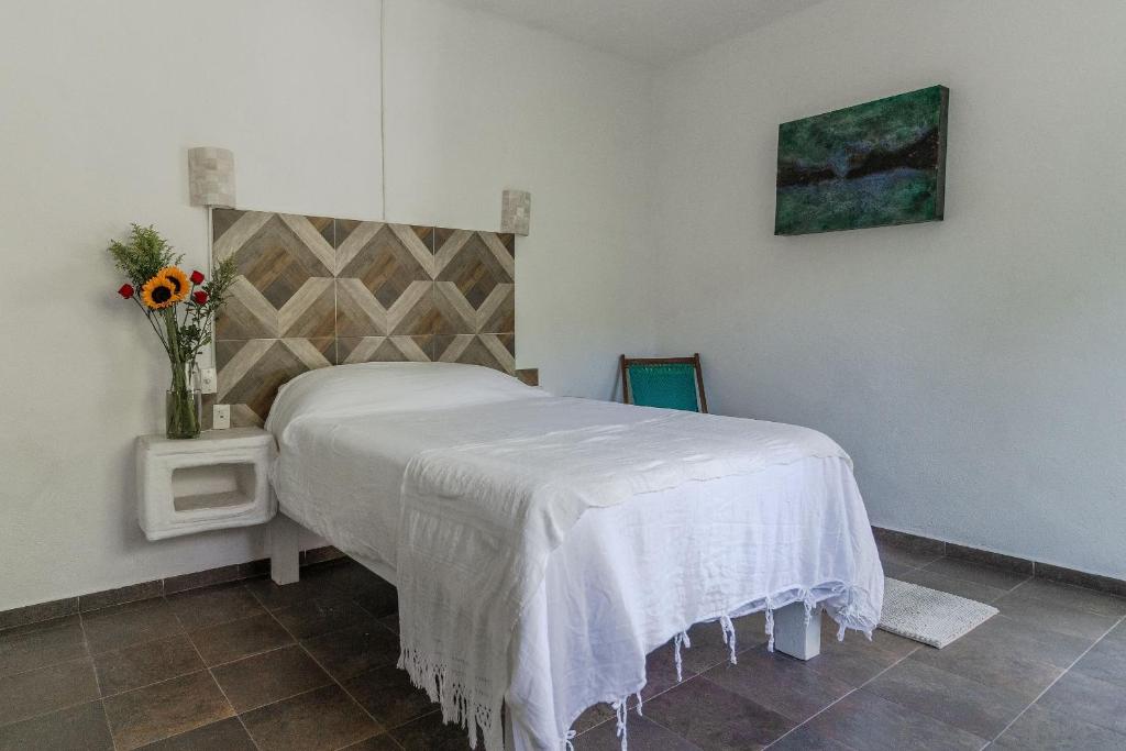a bedroom with a bed and a vase of flowers at Ecosoul Bugambilia villa in Puerto Vallarta