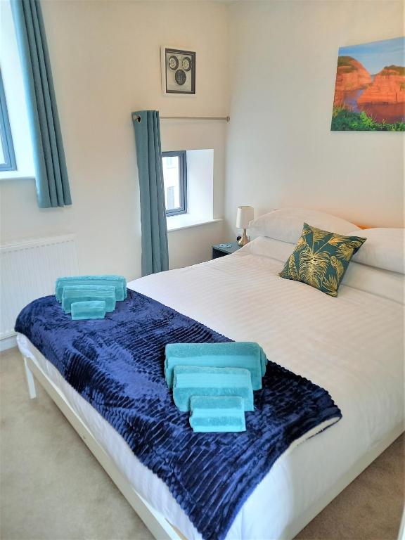 a bedroom with a white bed with blue towels on it at Goviers Cottage in Sidmouth