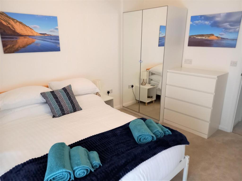ein Schlafzimmer mit einem weißen Bett und blauen Handtüchern darauf in der Unterkunft Goviers Cottage in Sidmouth