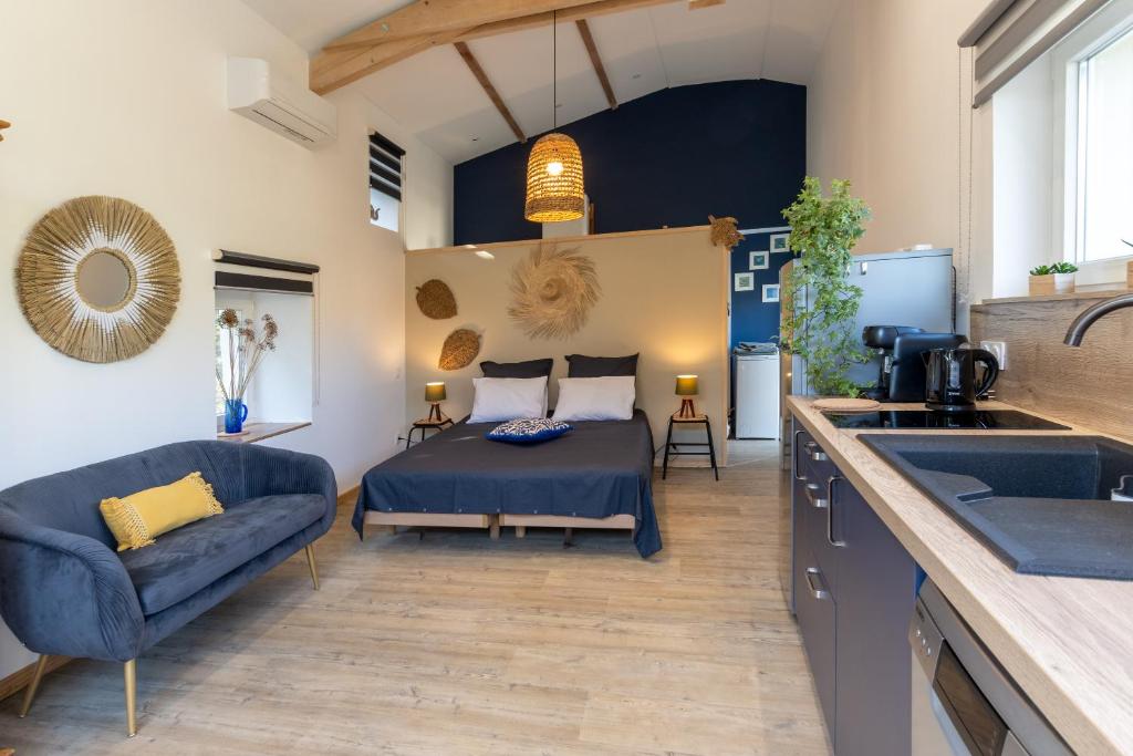 - une chambre avec un lit, un canapé et un lavabo dans l'établissement Les Oliviers - Le Chant des Tongs, à Salazac