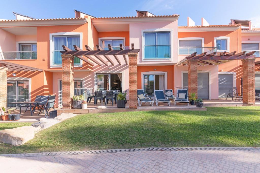 ein Haus mit einer Terrasse und Stühlen im Hof in der Unterkunft Jardins Vale de Santa Maria G, with pool in Albufeira