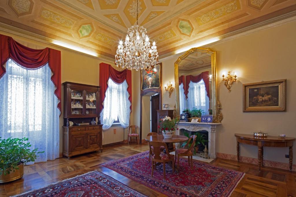 ein Wohnzimmer mit einem Kronleuchter, einem Tisch und Stühlen in der Unterkunft B&B Contrada dei Giardini in Cuneo