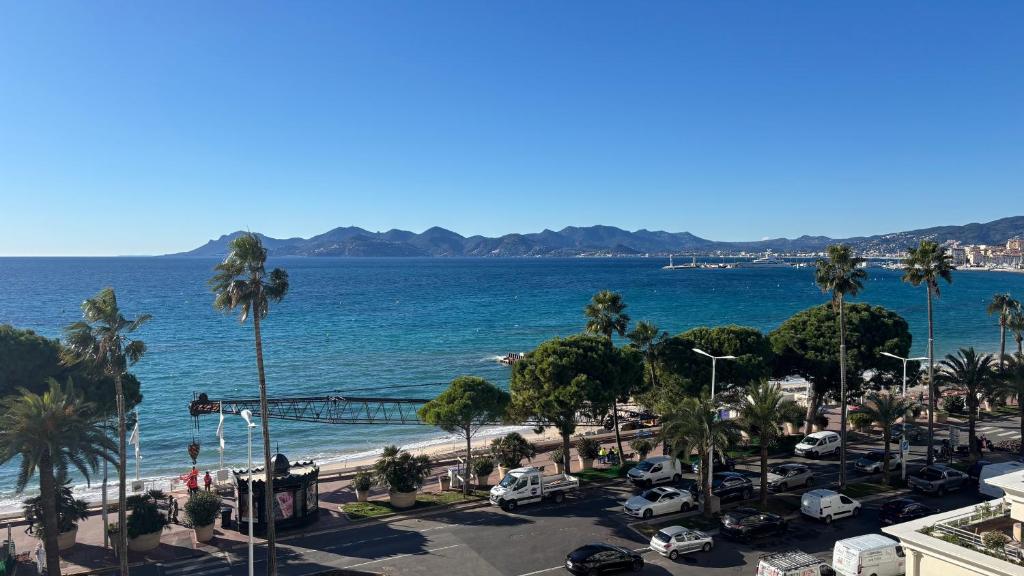 une vue sur une plage avec des palmiers et l'océan dans l'établissement Appartement Vue Panoramique - Croisette, à Cannes