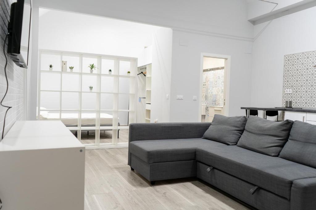 Hotel Casa Lealtad, a living room with a gray couch in a white room at Casa Lealtad in Seville
