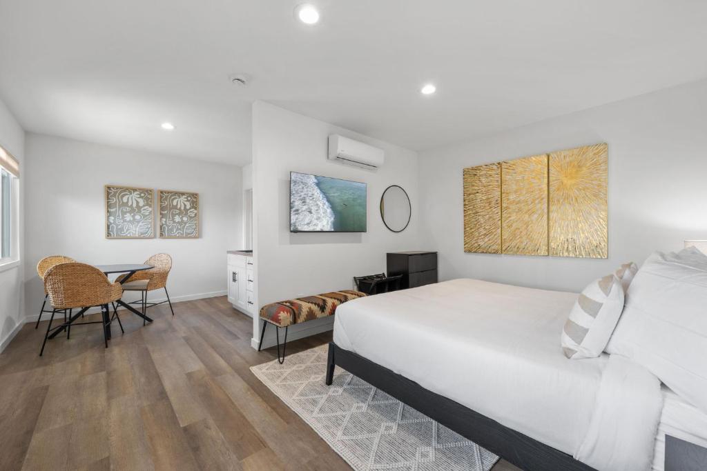 ein weißes Schlafzimmer mit einem Bett und einem Schreibtisch in der Unterkunft South O Bungalow 11 - Luxury King Suite + Patio in Oceanside