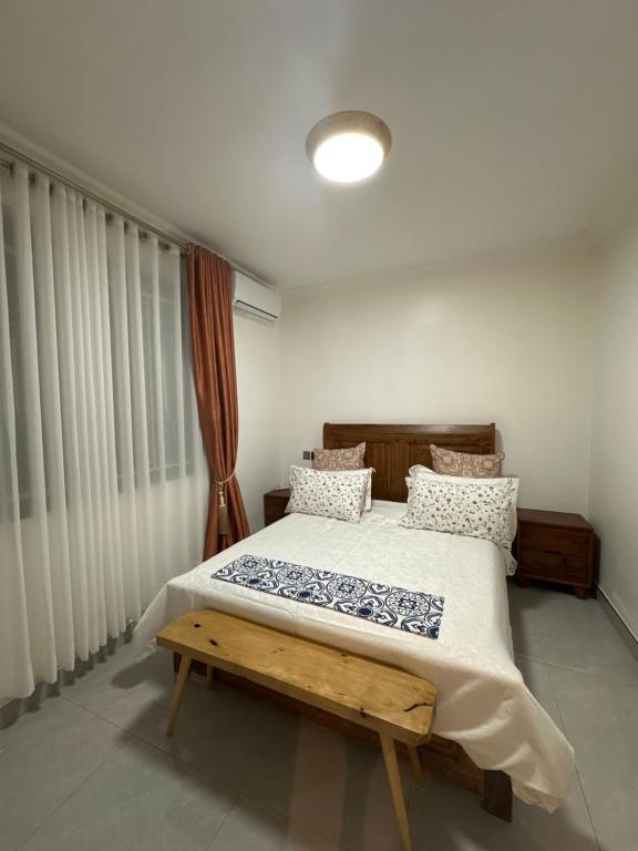 a bedroom with a bed and a bench in it at Flic and Flac Apartments Apt 6 in Kampala