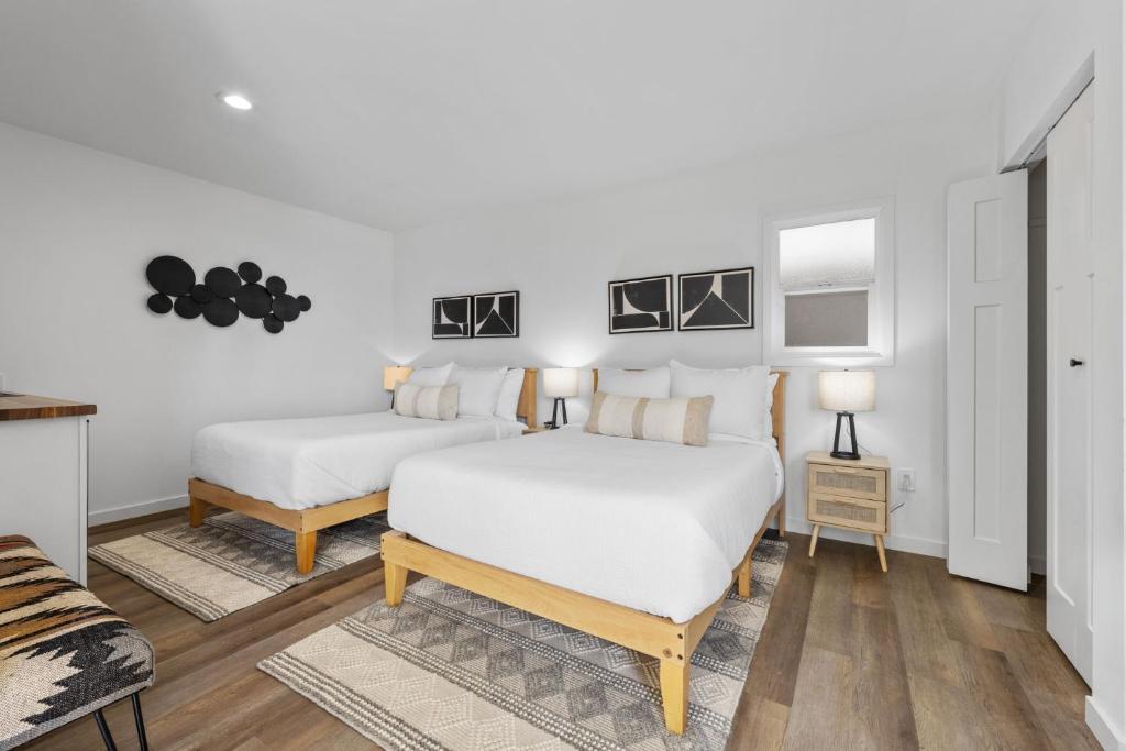 2 Betten in einem Zimmer mit weißen Wänden und Holzböden in der Unterkunft South O Bungalow 7 - Premium Double Studio + Patio in Oceanside