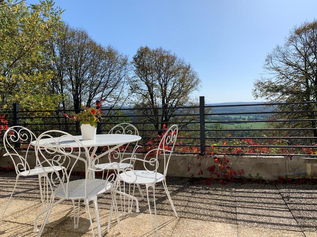 une table et des chaises sur une terrasse avec une clôture dans l'établissement Villa Séré de Rivières, au-dessus d'un fort, face aux Montagnes du Jura, à Fontain