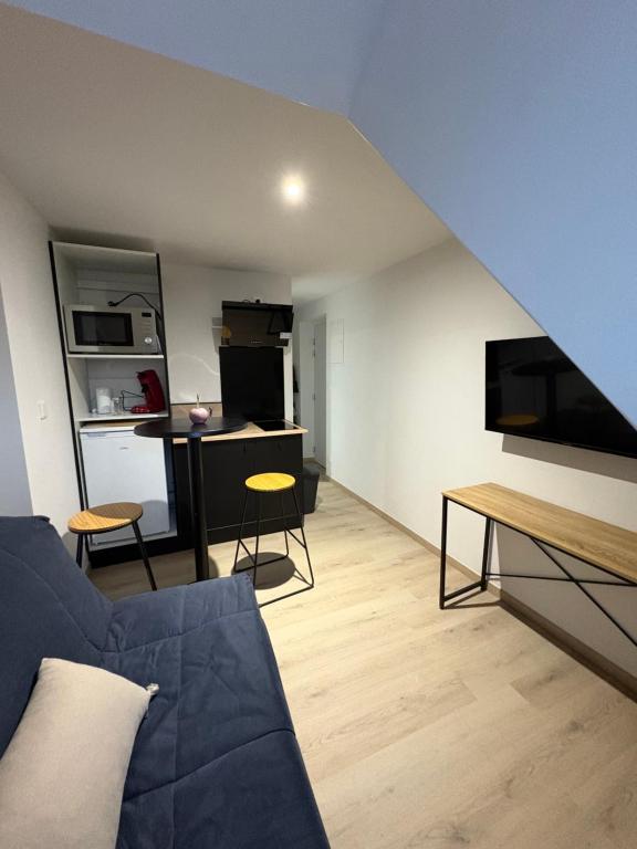 a living room with a blue couch and a kitchen at Le studio louana Appartement neuf et discret tout confort in Aubusson