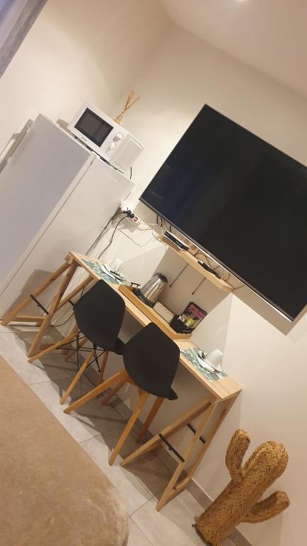 Elle comprend un bureau avec deux chaises et une grande télévision. dans l'établissement Chambre privée, à Porto-Vecchio