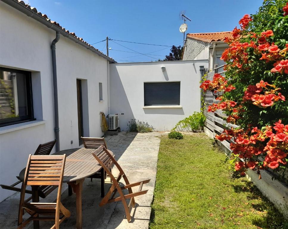 d'une terrasse avec une table et des chaises en bois dans la cour. dans l'établissement Maison Indépendante Climatisée à Deux Pas des Plages, Confort et Détente Assurés, à Royan