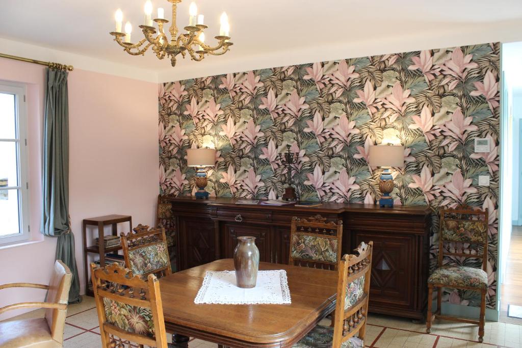 - une salle à manger avec une table, des chaises et du papier peint dans l'établissement La Georginette, à Saint-Georges-sur-Cher