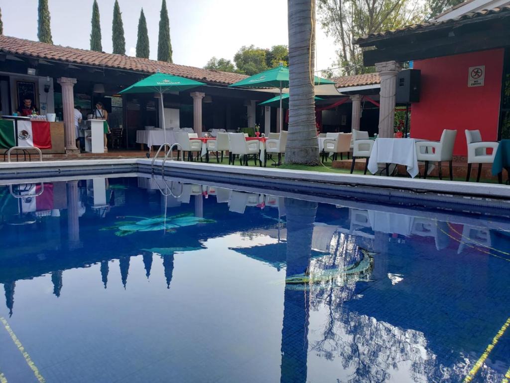 a swimming pool with tables and chairs next to a building at Hotel Casa Ixtapan, Ixtapan de la Sal in Ixtapan de la Sal