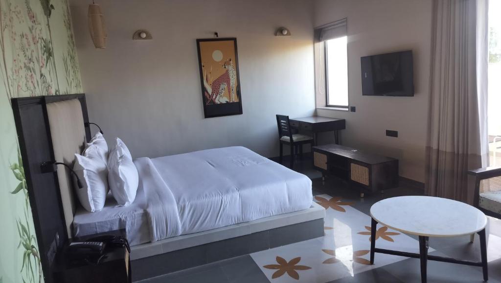 a bedroom with a bed and a table and a tv at The Forest Chapter by Sayaji, Jawai in Bīsalpur
