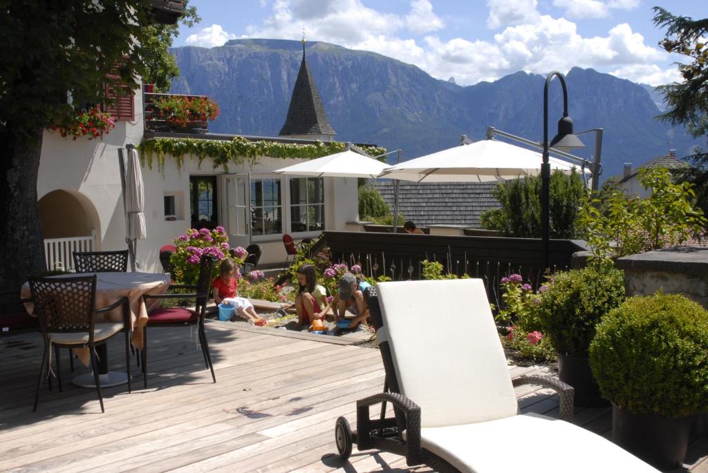 un patio con mesa, sillas y montañas en Hotel Dolomiten, en Collalbo