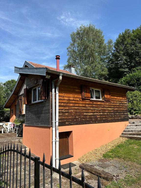 une maison avec une clôture devant dans l'établissement chalet cosy au calme, à Laveline