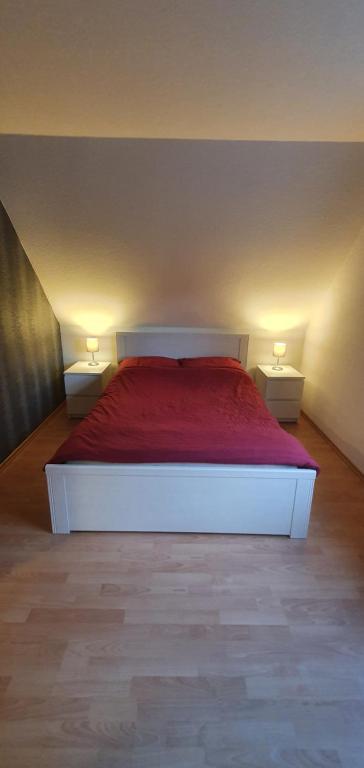 a bedroom with a white bed with a red blanket at Wohnung direkt an den Externsteinen in Horn-Bad Meinberg
