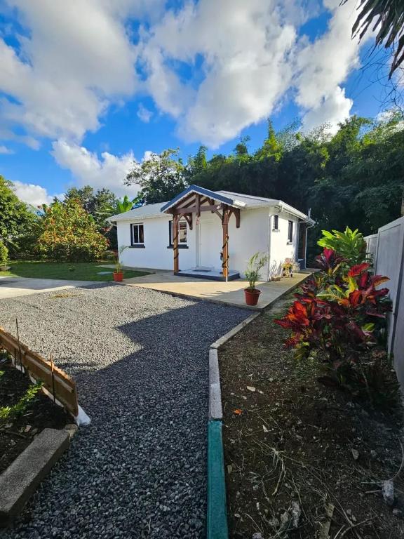 a small white house with a gravel driveway at Maison cosy à Lamentin, 20m², climatisation in Lamentin