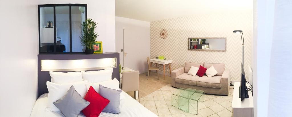 1 dormitorio con cama con almohadas rojas y sofá en Studio Premium Zénith Arènes Purpan, en Toulouse