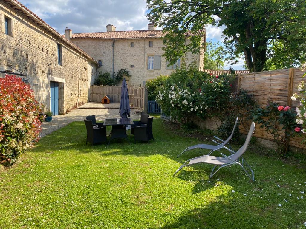 un patio avec une table et des chaises dans une cour dans l'établissement Gîte du Rossignol entre lac et forêt, à Mervent