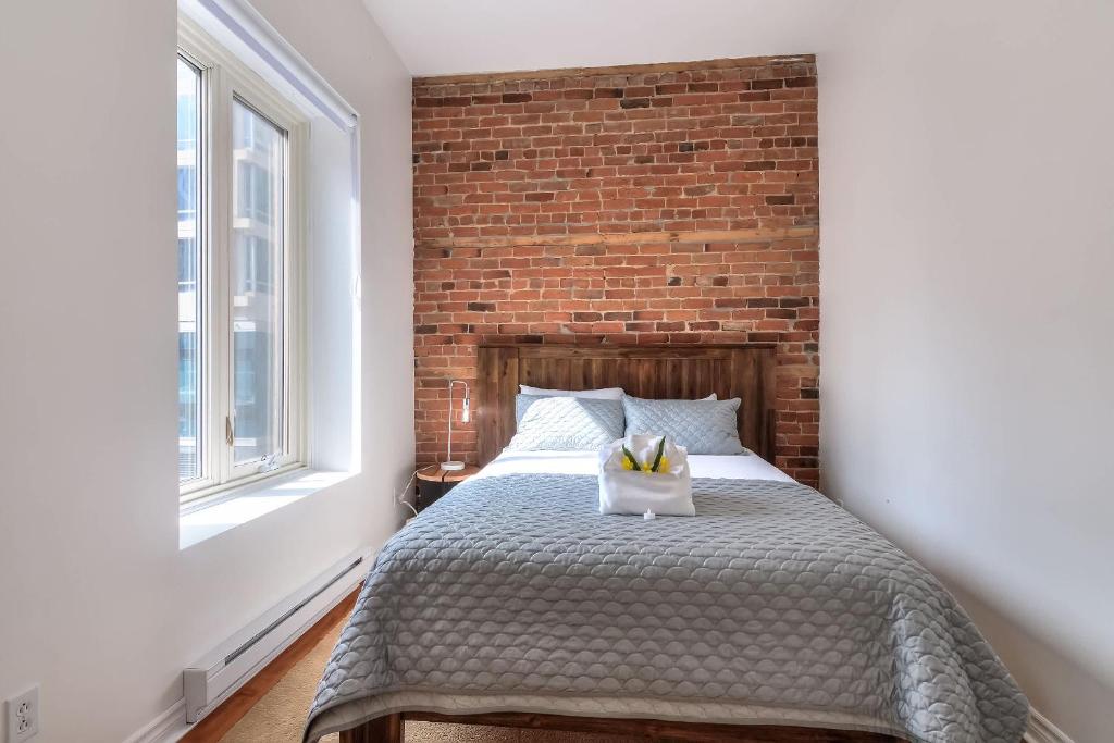una cama en una habitación con una pared de ladrillo en Fox Aparthotel Palais Des Congres IV, en Montreal