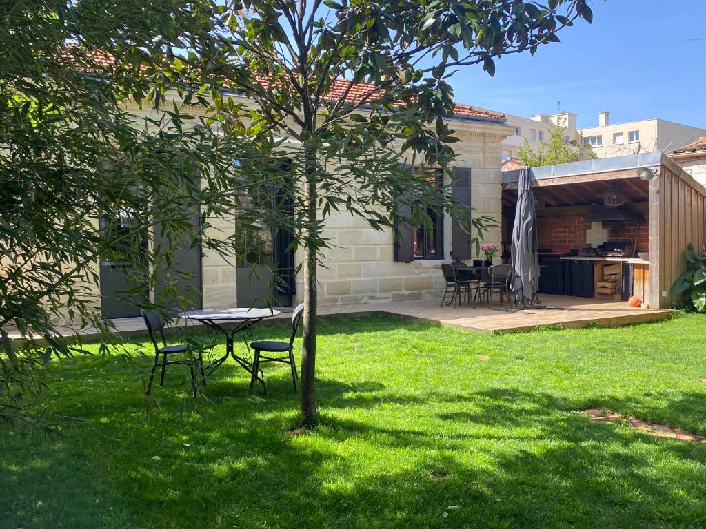 un patio avec une table et des chaises dans une cour dans l'établissement Maison Pierre avec Piscine, à Bordeaux