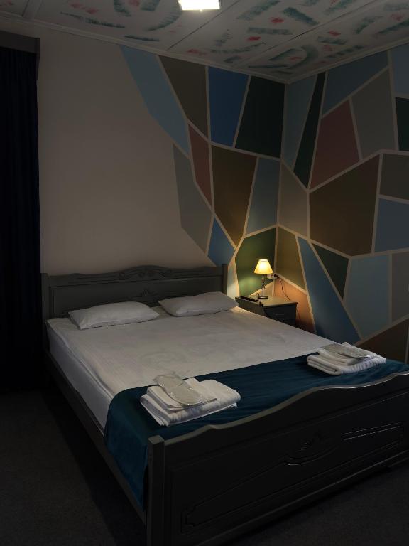 a bedroom with a bed with a geometric wall at Paxlava Dilijan Guesthouse & Restaurant in Dilijan