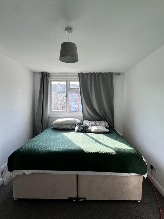 a bed with a green comforter in a bedroom at The best house in Whitchurch